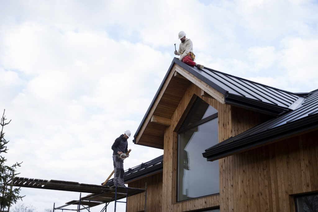 Roofing contractors installing a metal roof on a residential home, illustrating signs that homeowners may need roof replacement in Utah.